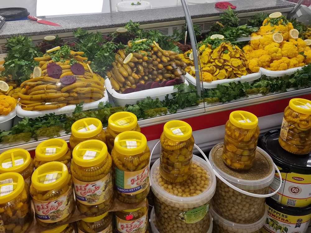 Kühltheke mit Torshi: eingelegte Gurken, Peperoni, Blumenkohl und Rote Bete, garniert mit Petersilie und Zitronen
