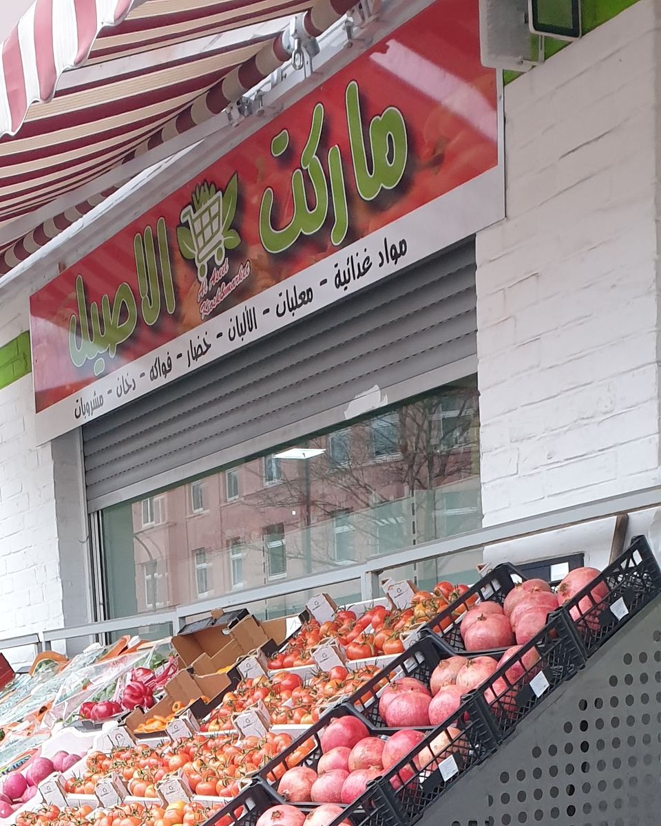 Arabisches Ladenschild über Granatäpfeln und Tomaten
